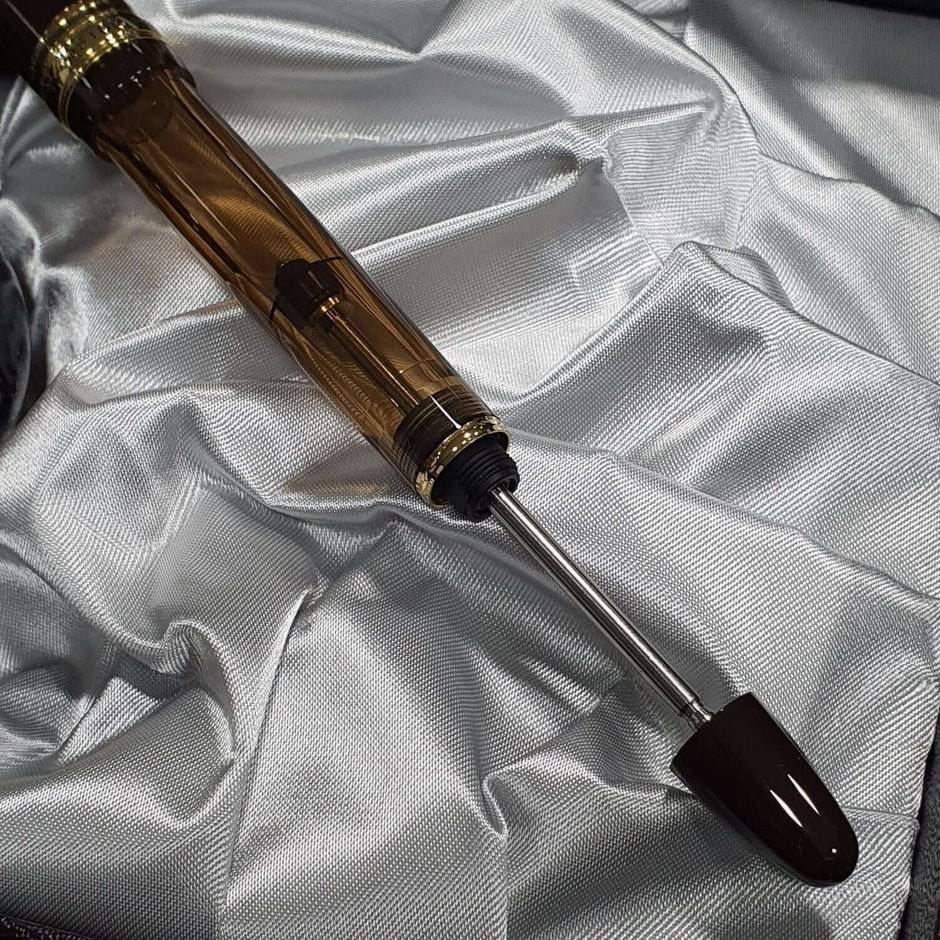 Pilot Custom 823 Amber Brown GT Fountain Pen with innovative plunger-type mechanism on soft fabric background.