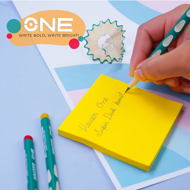 Person using Hauser Artz One Super Dark Pencil to write on a sticky note with a sharpener nearby.