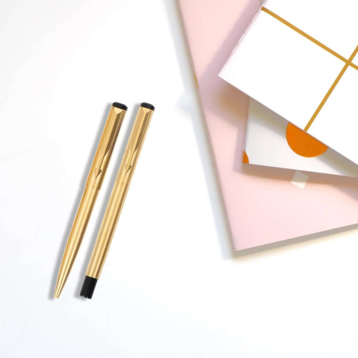 Parker Vector Gold Roller Ball Pen and Ball Pen with Card Holder elegantly displayed with stylish notebooks.