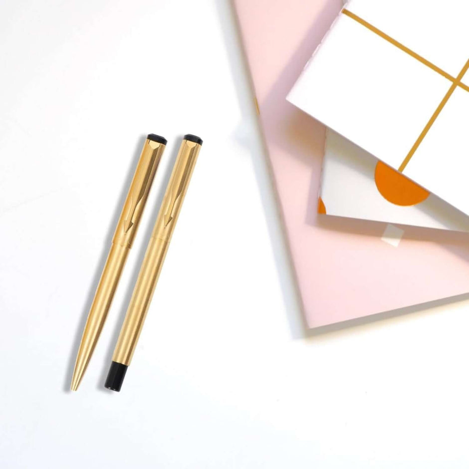 Parker Vector Gold Roller Ball Pen and Ball Pen with Card Holder elegantly displayed with stylish notebooks.