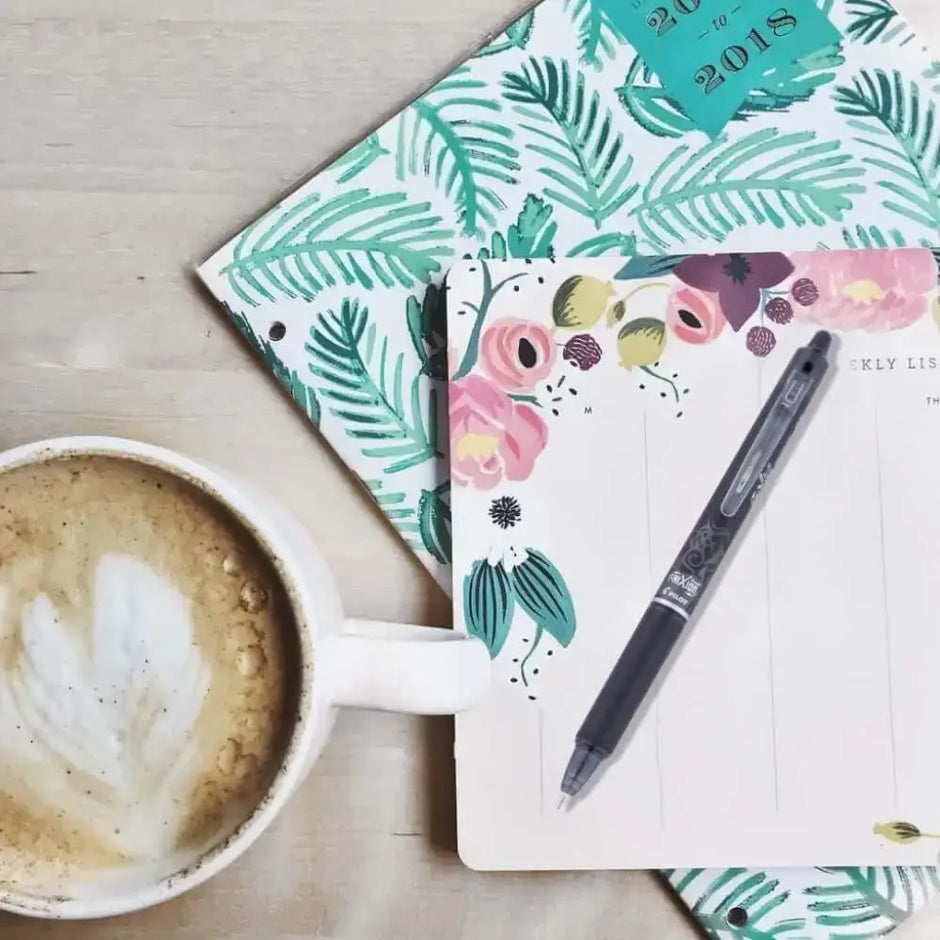 Pilot Frixion Clicker 0.7mm Fine Point Roller Ball Pen with Comfortable Dimpled Grip & Inbuild Eraser on a notebook with coffee.
