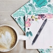 Pilot Frixion Clicker 0.7mm Fine Point Roller Ball Pen with Comfortable Dimpled Grip & Inbuild Eraser on a notebook with coffee.