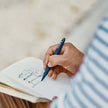 Person using Schneider One Business 0.6MM Roller Ball Pen to sketch in a notebook.