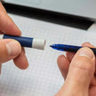 Hands holding Schneider One Change 0.6 MM Roller Ball Pen and exchangeable cartridge.