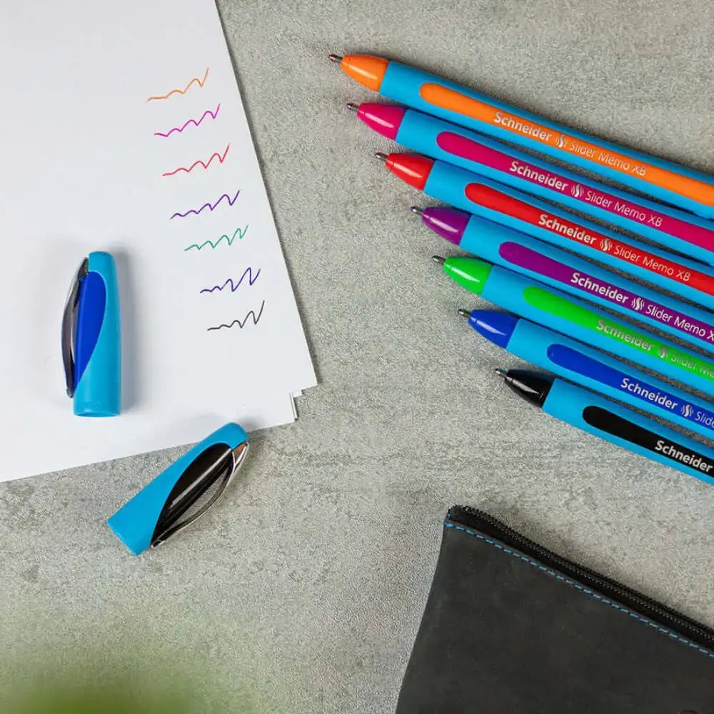 Schneider Slider Memo XB Ball Point Pen in various colors arranged beside a notepad with ink swatches.