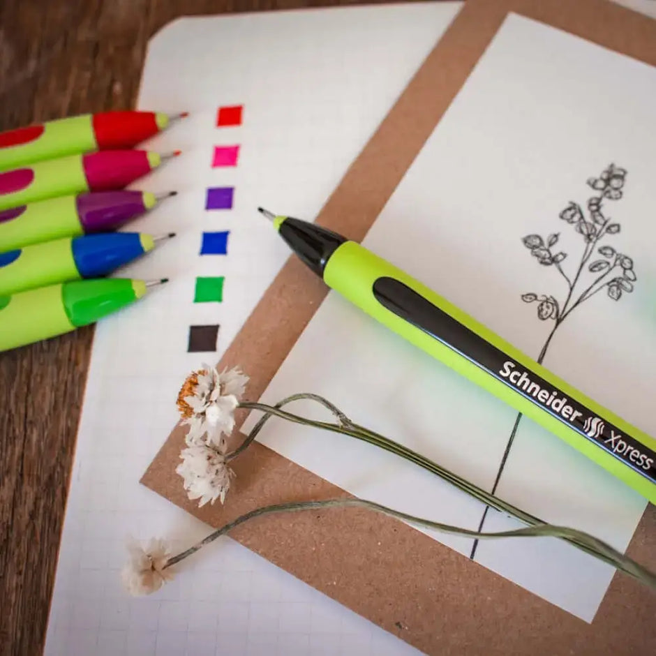 Schneider Xpress Fineliner 0.8 MM Pen beside colorful markers and a floral drawing on a notepad.